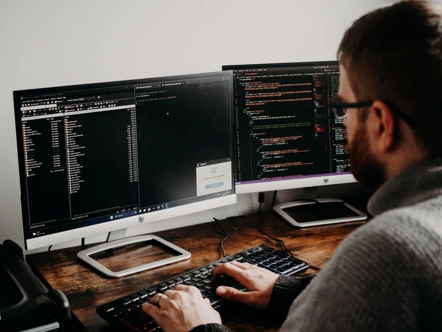 Seorang frontend developer sedang bekerja dengan kode HTML, CSS, dan JavaScript untuk merancang tampilan antarmuka web.