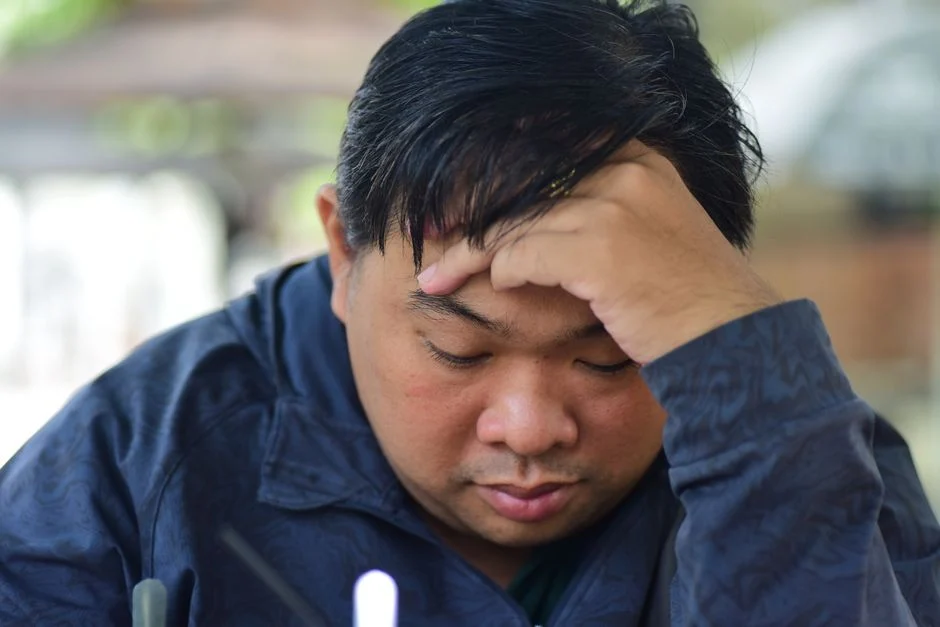 Seseorang yang terlihat sedang overthinking dengan tangan memegang kepala.